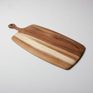 The Be Home Acacia Wood Rectangular Board with Handle Collection features striking light and dark grain patterns, elegantly displayed on a white surface.