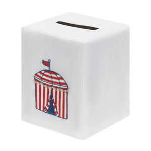Haute Home’s Beach Cabana Bath Collection features a white, cube-shaped tissue box cover crafted from premium Italian linen and adorned with an embroidered red and white striped cabana topped with a small flag.