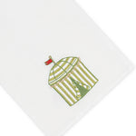 Haute Home’s Beach Cabana Bath Collection linen napkin features a white Italian linen fabric embroidered with a green and white striped cabana topped by a red flag.