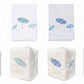 Eight white Italian linens from Haute Home’s Beach Umbrella Bath Collection: four flat linens with embroidered umbrellas in green, blue, or red; and four premium linen tissue box covers, each featuring matching umbrella embroidery.