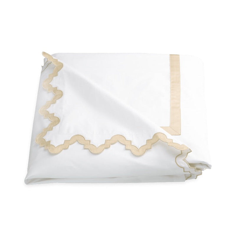 Matouk Aziza Bedding Collection, Champagne, white folded 600 thread count Egyptian cotton percale duvet cover with a tan scalloped embroidered border.