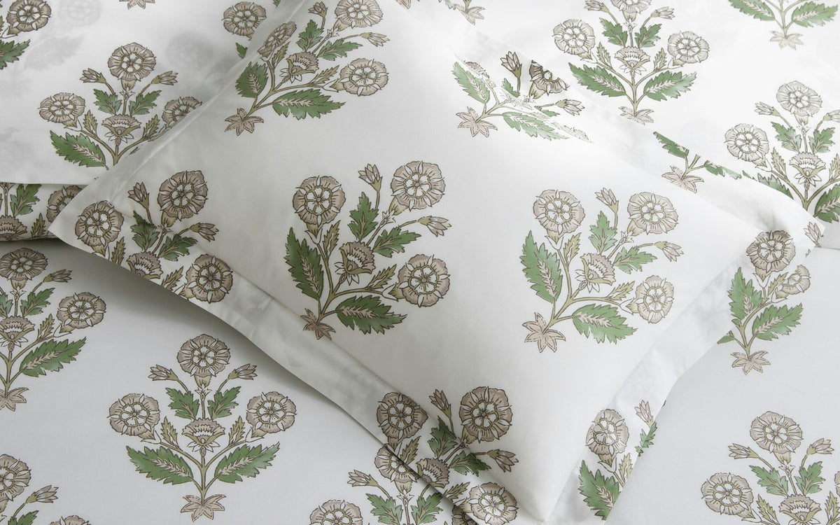 Dalila Bedding Collection by Matouk, featuring a white fitted sheet and pillow covered in a lively green and beige floral pattern inspired by Schumacher block print, crafted from soft Luca percale and viewed from above.