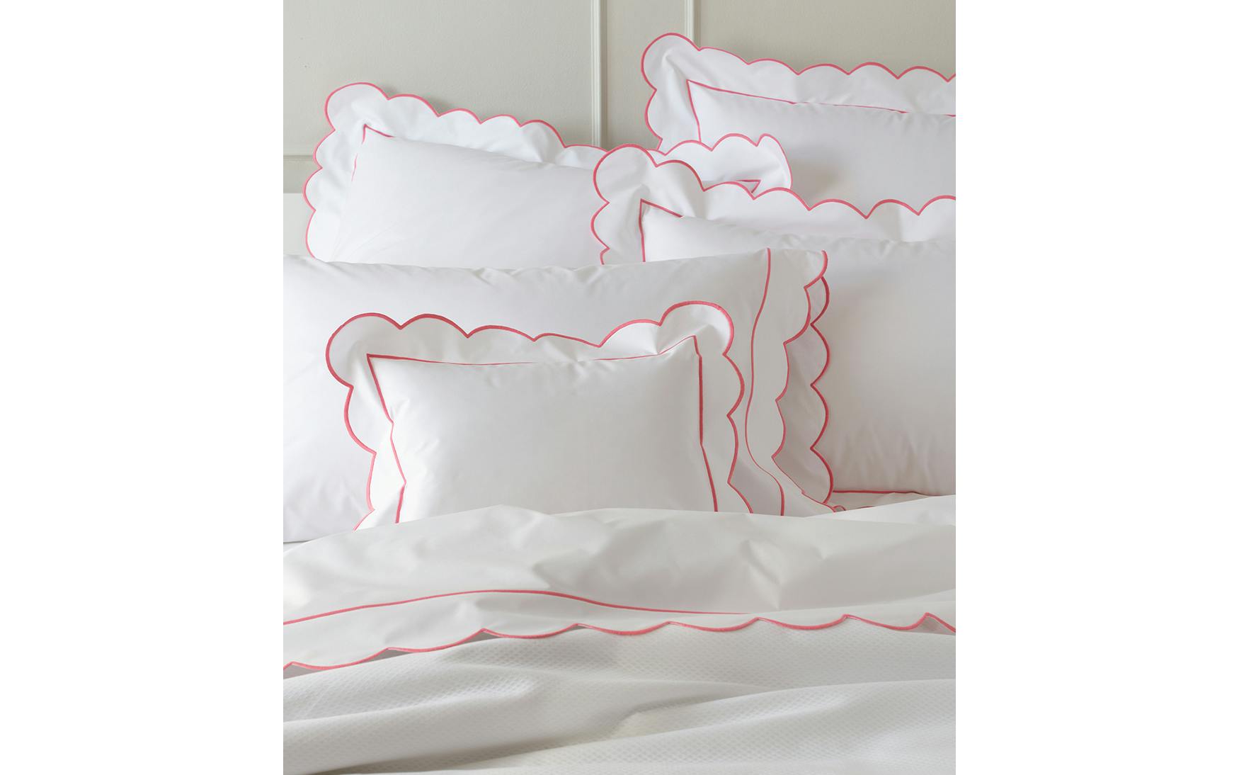 The Butterfield Bedding Collection, Azalea by Matouk features luxurious Egyptian cotton percale with white pillows and bedding, delicately scalloped and finished with pink piping for an elegant touch.