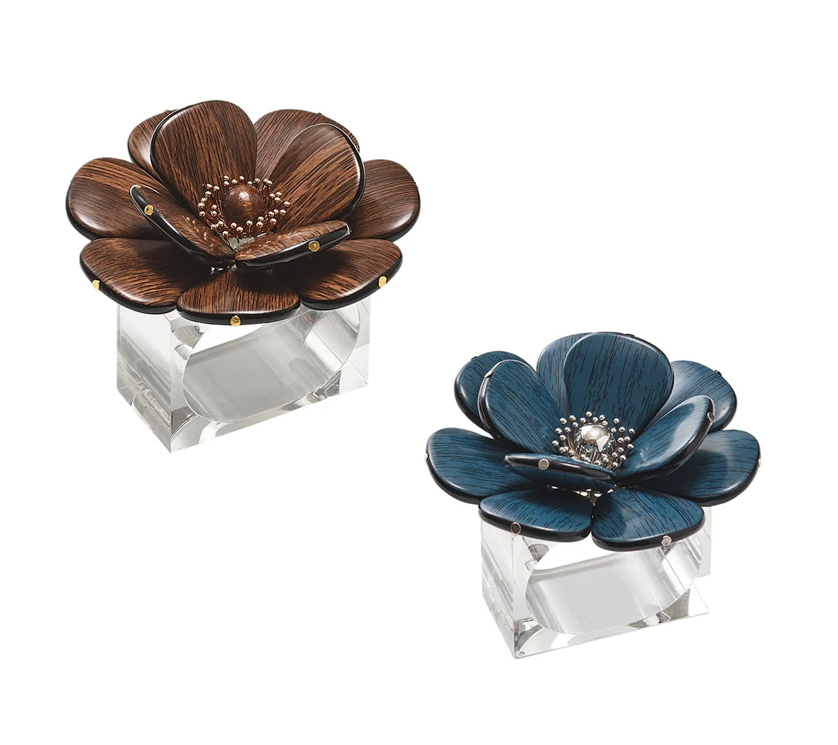 Two Kim Seybert Begonia Napkin Rings, one in a rich brown reminiscent of faux wood and the other in a striking blue—each adorned with metallic accents—are elegantly displayed on clear rectangular bases against a white background.