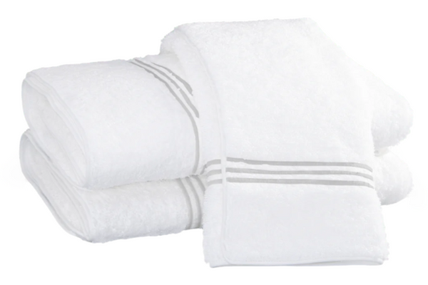 A stack of three luxurious towels from the Matouk Bel Tempo Bath Collection, designed with Cairo long-staple cotton and featuring sophisticated silver stripes on a white background.