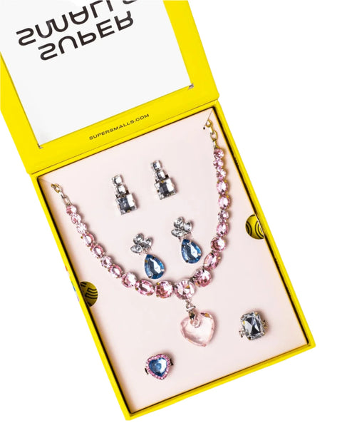 The Super Smalls Big Presentation Jewelry Set by Super Smalls arrives in a delightful yellow box and includes a pink beaded necklace with a heart pendant, two pairs of earrings, and two rings embellished with extra-sparkly jewels. It's an ideal choice for anyone who loves pastel elegance.