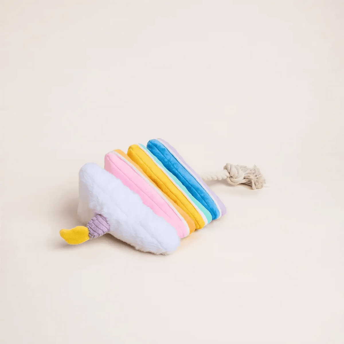 The Foggy Dog Birthday Cake Interactive Snuffle Dog Toy, featuring a pastel-colored popsicle shape with a yellow tip and a tug-friendly rope handle, is displayed on a plain cream background.