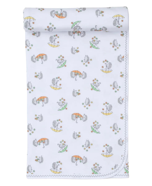 A rolled-up white Kissy Kissy Hedgehog Fall Showers Printed Blanket showcases a whimsical pattern featuring animals with hats, umbrellas, and flowers. Made from luxurious Pima cotton, the edges boast a charming zigzag stitch design.