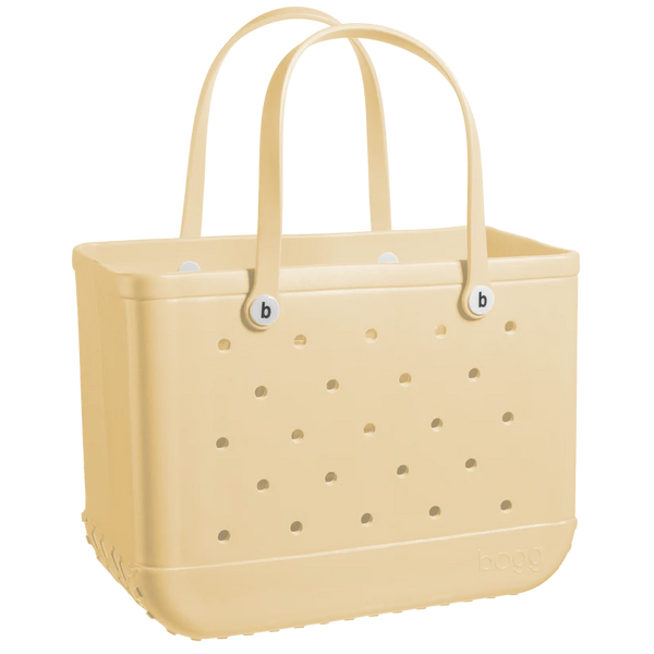 A beige, rectangular Original Bogg Bag tote from Bogg Bags with perforated sides and two sturdy handles. The bag has circular holes arranged in rows, and the brand name "bogg" is embossed on the lower right corner. Known for its durable tote and washable design, it's as practical as it is stylish.