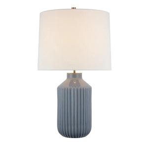 The Braylen Medium Ribbed Table Lamp by Visual Comfort features a ribbed blue ceramic base inspired by dinnerware motifs and is topped with a large white linen shade.
