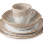 The Burlington Bluff Dinnerware Collection by Simon Pearce is a four-piece ceramic set—plate, salad plate, cereal bowl, and mug—with beige and white Bluff glaze inspired by classic pinch-pot style.