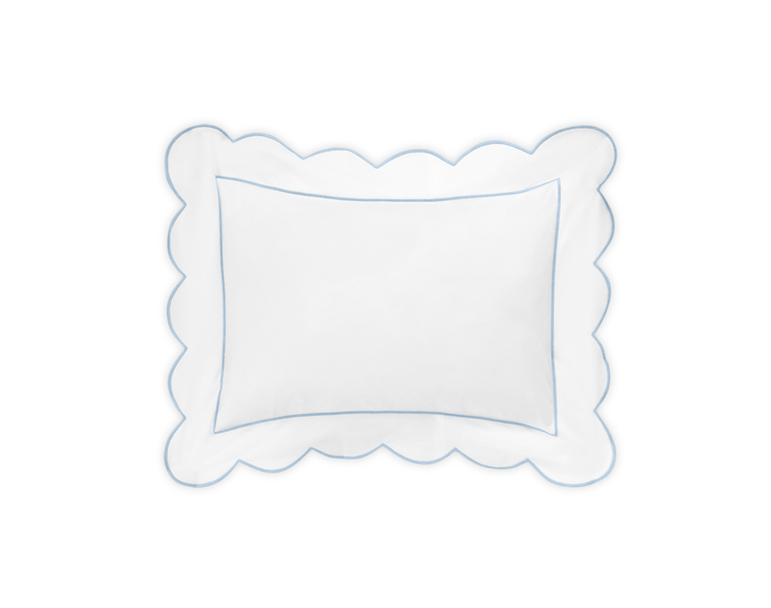 A white rectangular pillow from the Butterfield Bedding Collection by Matouk features scalloped edges and a blue border in luxurious 500 thread count Egyptian cotton percale, set against a black background.