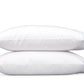 Two white pillows from the Matouk Butterfield Bedding Collection are stacked one atop the other against a plain white background, their luxurious softness and refined finish perfectly complementing Egyptian cotton sheets.