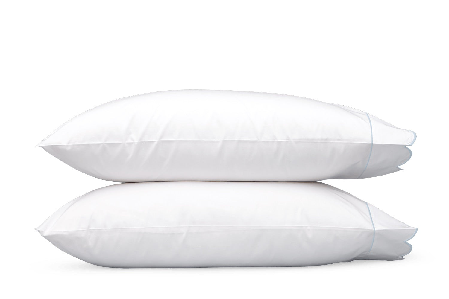 Two white pillows from the Matouk Butterfield Bedding Collection are stacked one atop the other against a plain white background, their luxurious softness and refined finish perfectly complementing Egyptian cotton sheets.
