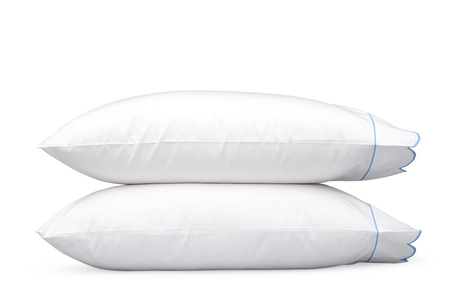 Two white pillows from the Butterfield Bedding Collection by Matouk, featuring elegant blue piping and a subtle scallop detail, are stacked together against a plain white background—an ideal complement to Egyptian cotton or crisp percale sheeting.