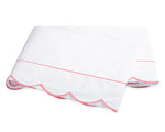 The Butterfield Bedding Collection by Matouk showcases a white folded bedsheet crafted from luxurious percale sheeting, accented with a pink scallop detail and a delicate pink line near the edge, displayed on a plain background.