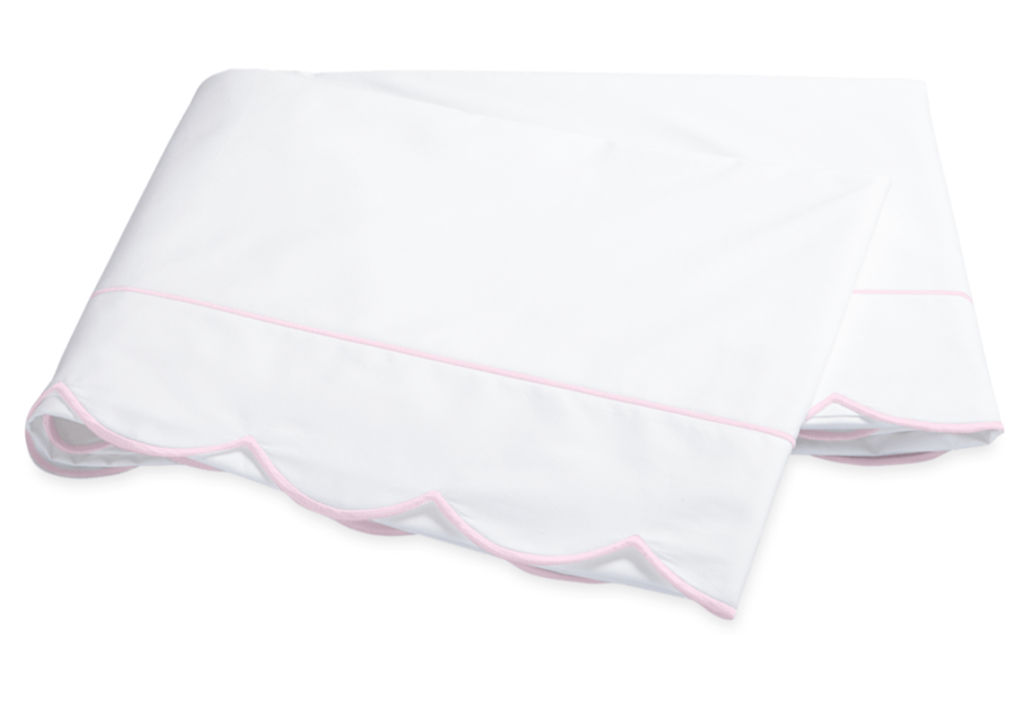 Two folded white pillowcases from the Matouk Butterfield Bedding Collection, featuring light pink piped edges and scallop detail, crafted from Egyptian cotton percale.