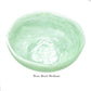 The Mint Resin Serveware Collection by Nashi Home features a medium, light green marbled bowl made from shatter-resistant resin, styled as "Wave Bowl Medium"—a chic accent for any home decor.