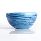 A round ceramic bowl with blue and white marbled patterns, displayed on a reflective white surface—perfect as shatter-resistant decor or paired with the Denim Resin Serveware Collection from Nashi Home for a stylish touch.