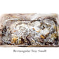 The Mocha Resin Serveware Collection by Nashi Home features a small rectangular tray with a marbled brown, gray, white, and gold pattern. This food-safe resin piece adds a touch of elegance to your decor. Text: "Rectangular Tray Small.