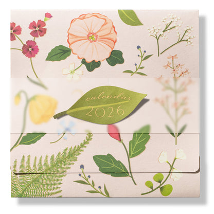 The 2026 Classic Desk Calendar Collection by Karen Adams features a floral design on a light background with illustrated flowers, leaves, and a green leaf-shaped "calendar 2026" label—an ideal gift inspired by best-selling calendar styles.