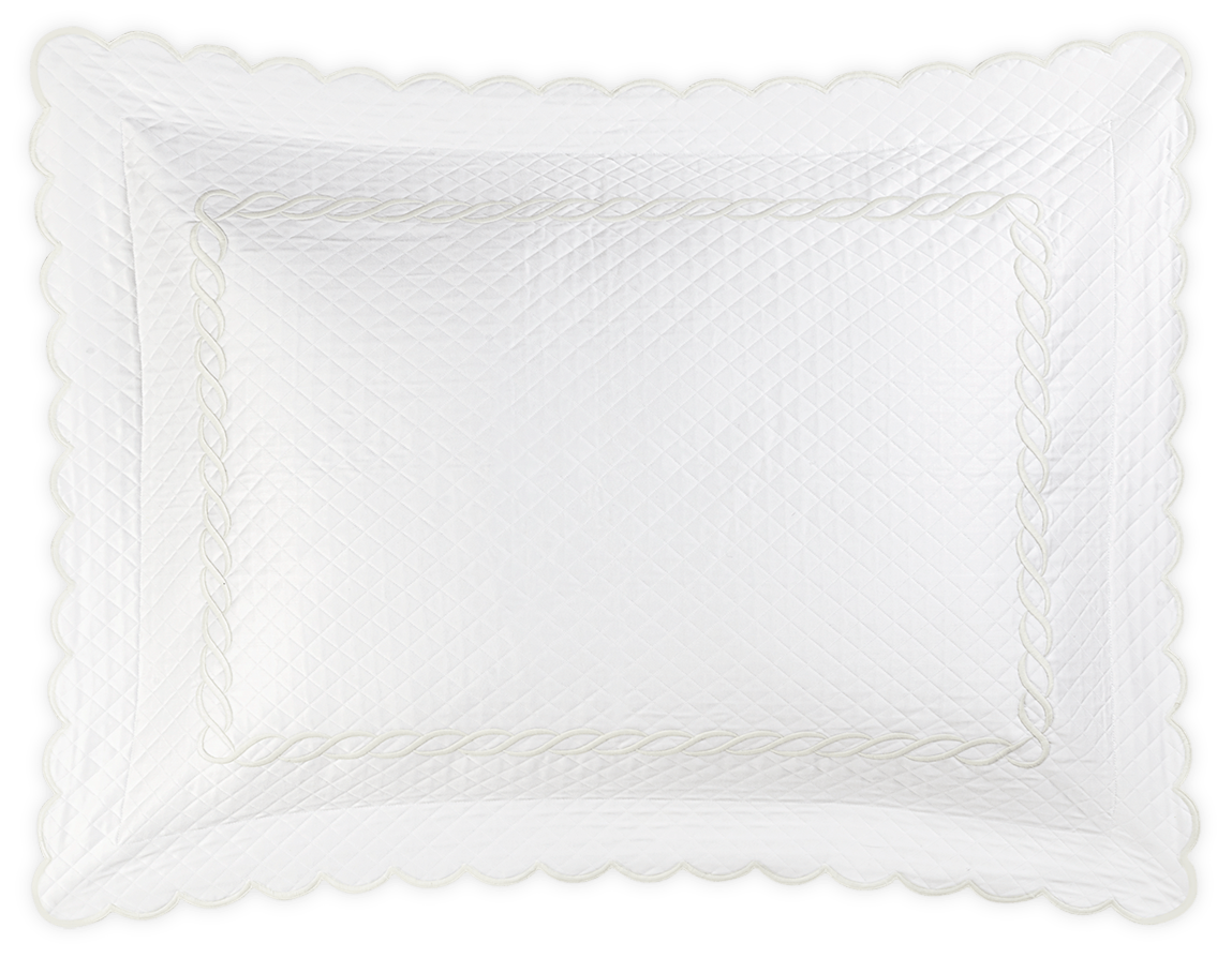The Matouk Classic Chain Scallop Matelassé Bedding Collection in white features a rectangular quilted pillow sham with scalloped edges, diamond pattern, decorative stitched border, and elegant embroidery motifs, shown on a black background.