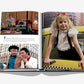 An open book, "5th Avenue" by Assouline, displays scenes: a child in a yellow taxi on Fifth Avenue, two men talking on the street, and hotel room service—each image accompanied by text.
