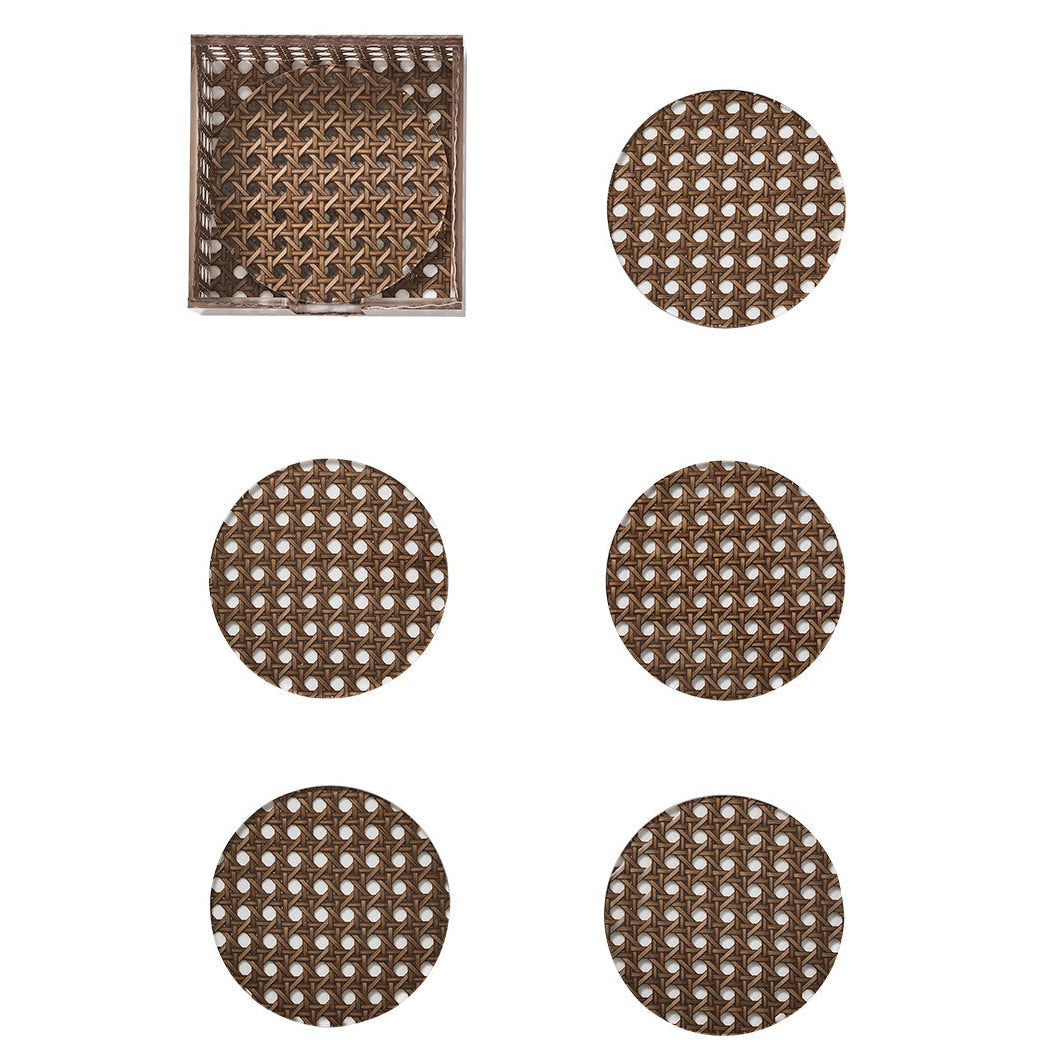 The Kim Seybert Reed Brown Coaster Set includes six round faux-wicker coasters with lattice cutouts, displayed with one in a square holder. Stylish and practical, they're ideal for outdoor drinks.