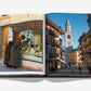 Assouline's "Cortina d'Ampezzo" book open to photos: left, two people in winter coats view a shop window; right, a street scene of Cortina d’Ampezzo with colorful buildings and Dolomites rising behind a church tower.