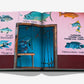 Open book displaying a page with a pink wall, painted fish, and a door opening to fishing gear; vibrant text invites readers to embark on the ultimate Costa Rica Vida adventure by Assouline—experience real Pura Vida.