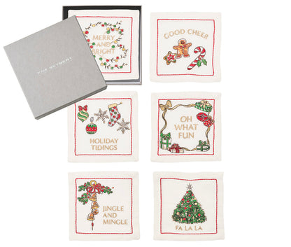 The Kim Seybert Merry and Bright Cocktail Napkin Set features six embroidered holiday napkins with festive designs, beautifully packaged in a gray branded box—perfect as a hostess gift or to elevate your holiday table linens.