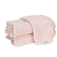 Two folded light pink luxury bath towels from the Matouk Cairo Scallop Bath Collection, featuring elegant white scalloped trim and expertly crafted in the USA from long-staple cotton, stacked on a white background.