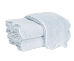 A neatly folded stack of light blue Matouk Cairo Scallop Bath Collection luxury towels with white trim, displayed on a plain white background.