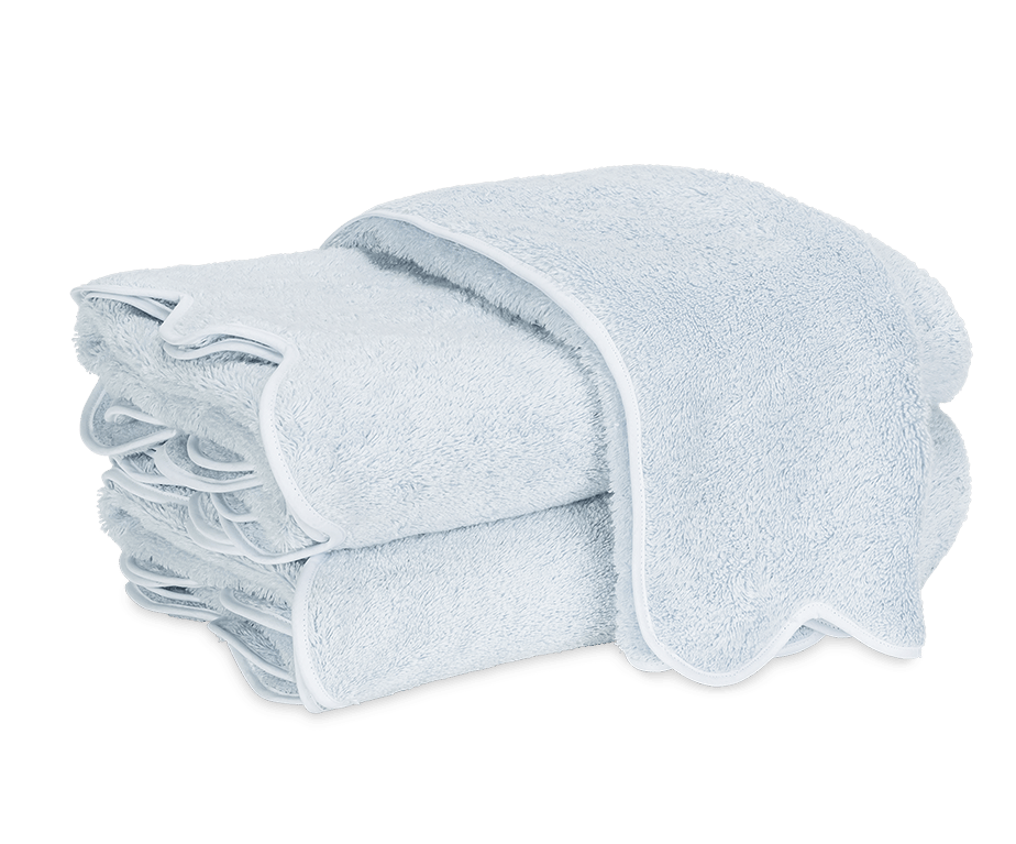 A neatly folded stack of light blue Matouk Cairo Scallop Bath Collection luxury towels with white trim, displayed on a plain white background.