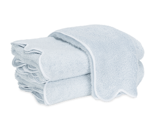 A neatly folded stack of light blue Matouk Cairo Scallop Bath Collection luxury towels with white trim, displayed on a plain white background.
