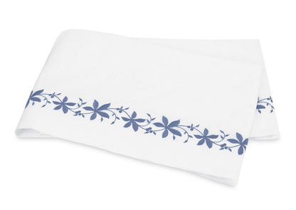 A folded white sheet from the Callista Bedding Collection by Matouk, featuring a blue floral pattern along the edge, crafted from luxurious Giza Egyptian cotton with a 500 thread count, and displayed on a plain background.