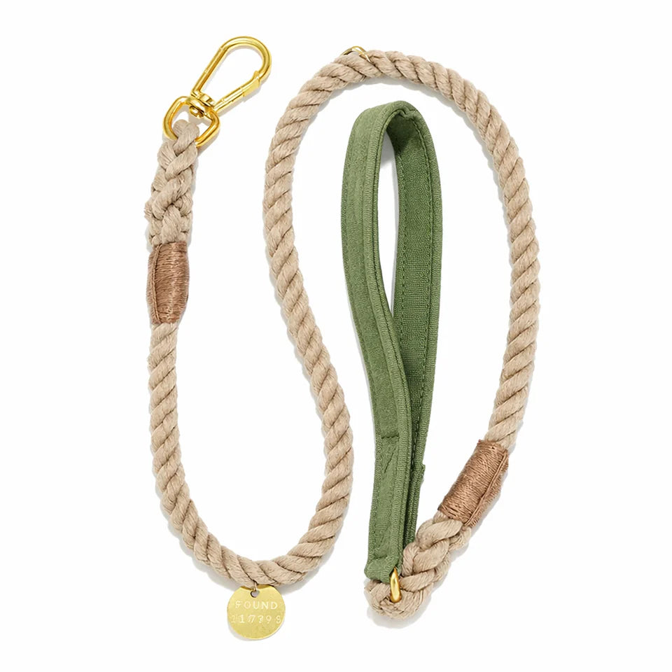 The Found My Animal Waxed Cotton Canvas Leash Collection features a beige handcrafted leash with a gold metal clip, brown accent wraps, green fabric handle, and a round gold tag for stylish flair.
