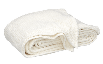 The Matouk Chatham Blanket in Ivory, crafted from 100% cotton with a waffle weave, is made in Portugal and shown folded against a white background.
