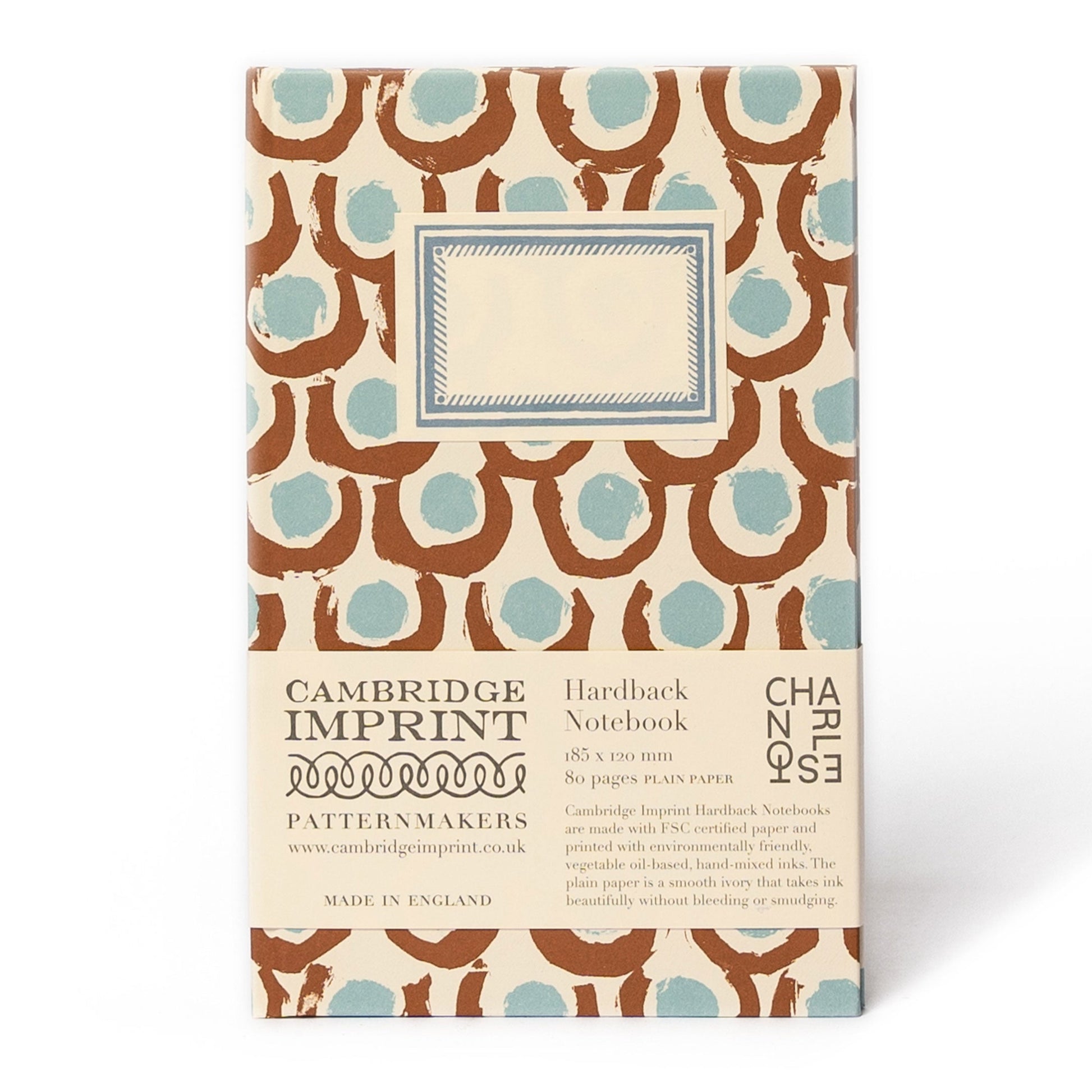 The Chic Gift Hamper by Sharland England includes a stylish hardback notebook with a brown and blue pattern, a blank cover label, and a branded sleeve—ideal for pairing with artisanal treats like hand-poured candles.