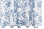 The Chrysanthemum Shower Curtain Collection by Matouk features slightly sheer white fabric with a repeating blue chrysanthemum motif in the Tillett style, designed to hang in gentle folds.