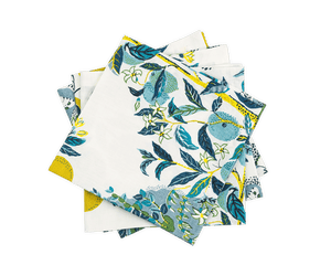 A stack of folded cloth napkins from Matouk's Citrus Garden Pool Collection, featuring a blue, green, and yellow botanical print with leaves and fruits on white—perfect to pair with a linen tablecloth.