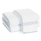 Two folded white cotton terry towels from the Matouk Classic Chain Bath Collection, featuring light blue embroidered borders and a twisted rope design, are stacked on a plain white background.