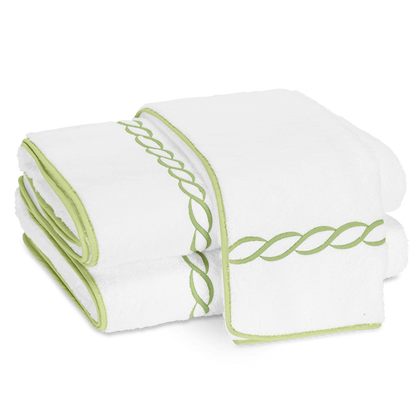 Two folded Matouk Classic Chain Bath Collection cotton terry towels with light green trim and a signature chain embroidered border, displayed side by side on a plain background.