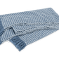 The Cleo Throw Collection by Matouk features a blue and white cashmere throw with fringe and a basketweave pattern, elegantly displayed flat.