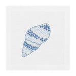 A white linen napkin with an embroidered blue and light blue seashell design pairs beautifully with Haute Home’s Speckled Conch Coaster Set for an elegant coastal accent to your table setting.