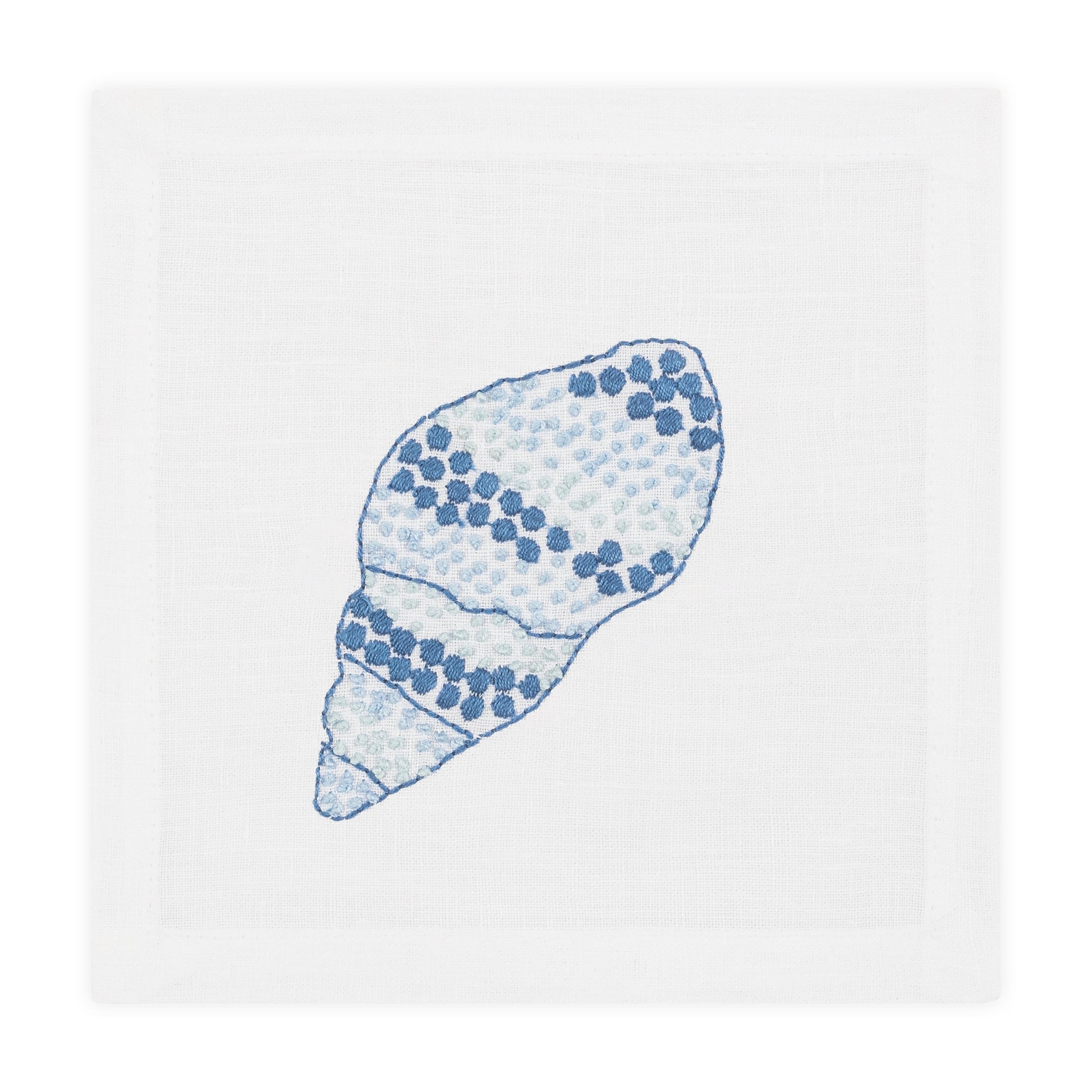 A white linen napkin with an embroidered blue and light blue seashell design pairs beautifully with Haute Home’s Speckled Conch Coaster Set for an elegant coastal accent to your table setting.