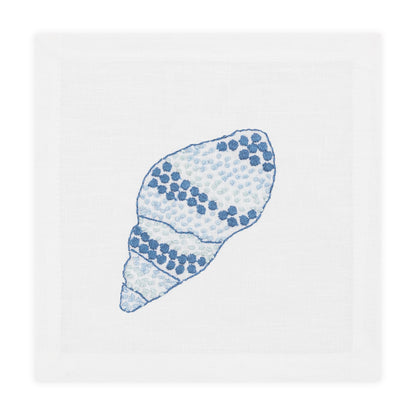 A white linen napkin with an embroidered blue and light blue seashell design pairs beautifully with Haute Home’s Speckled Conch Coaster Set for an elegant coastal accent to your table setting.