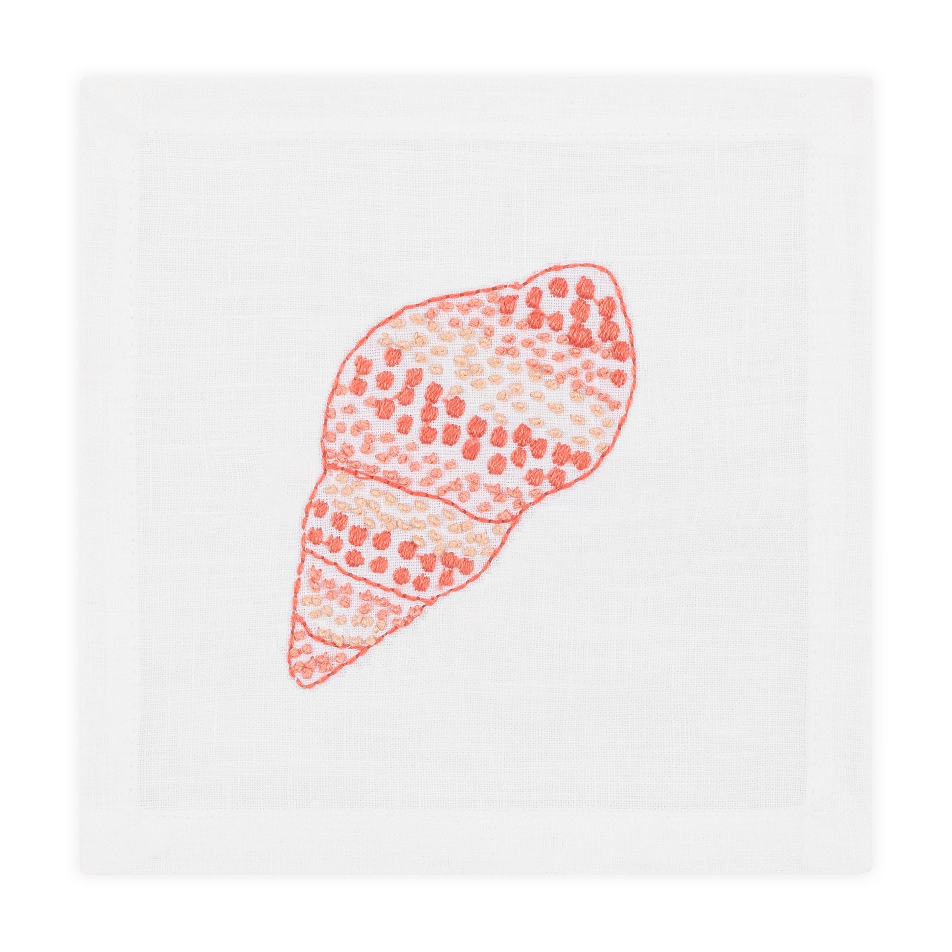 Haute Home’s Speckled Conch Coaster Set pairs perfectly with a white cloth napkin featuring an embroidered orange and pink seashell for a stylish, coastal-inspired table setting.