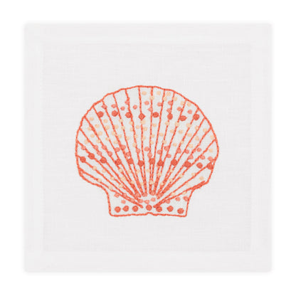 The Speckled Shell Coaster Set by Haute Home features white Italian linen coasters with an orange hand-embroidered seashell in the center.