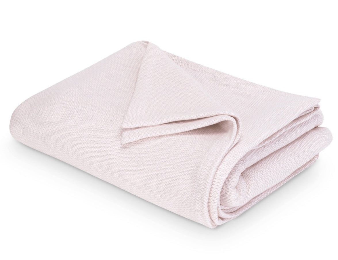 The Costa Mesa Blanket Collection by Matouk features a soft, light pink knitted blanket displayed on a white background.